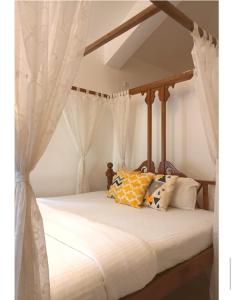 Ronne's Casa De Piscina Privada 3BHK VILLA في Verla: غرفة نوم مع سرير مظلة مع ستائر بيضاء