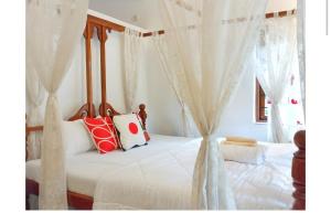 Schlafzimmer mit Himmelbett und weißen Vorhängen in der Unterkunft Ronne's Casa De Piscina Privada 3BHK VILLA in Verla