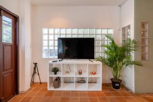 a living room with a tv on a white cabinet at Thonglor House by Panisa in Klong Toi