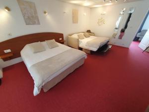 a bedroom with two beds and a red carpet at Logis Hôtel Restaurant L'Odyssée Champêtre in Le Lude