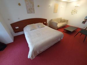 1 dormitorio con 1 cama, 1 sofá y 1 silla en Logis Hôtel Restaurant L'Odyssée Champêtre, en Le Lude