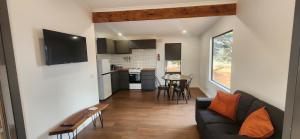 a living room with a couch and a table at Glossy Black Cabin in Parndana