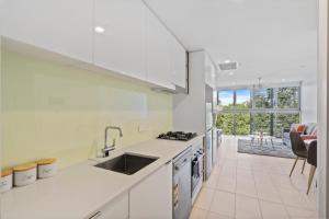 a white kitchen with a sink and a stove at Cozy 1 bedroom in the Heart of South Brisbane with parking in Brisbane