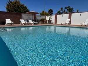 ein großer Pool mit Stühlen und einem Sonnenschirm in der Unterkunft Bajamar-Campo de Golf frente al mar in Ensenada