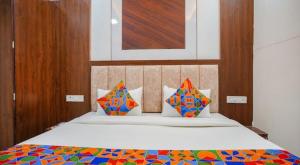 um quarto com uma cama com lençóis e almofadas coloridos em Hotel Coral em Indore