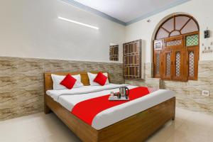 Schlafzimmer mit einem Bett mit roten und weißen Kissen in der Unterkunft Flagship Hotel Venus in Kānpur
