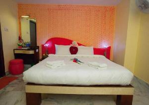 a bedroom with a large bed with a red headboard at OYO Hotel Nico in Port Blair