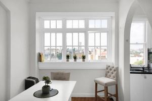 a white kitchen with a table and a window at Kadina Harbourside Studio - A Cosy Panoramic Gem in Sydney