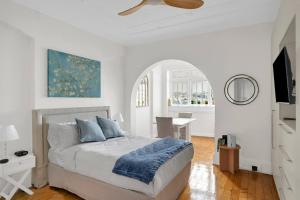 a white bedroom with a bed and a ceiling fan at Kadina Harbourside Studio - A Cosy Panoramic Gem in Sydney