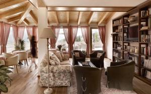 ein Wohnzimmer mit Sofa und Bücherregal in der Unterkunft Hotel Garnì Carpe Diem in Vigo di Fassa