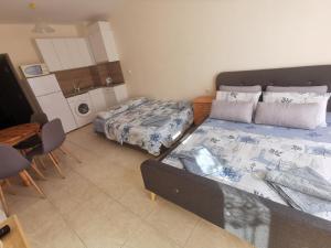 a bedroom with two beds and a table and a kitchen at Студиa Блу минута от плажа in Pomorie