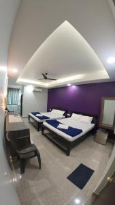 a bedroom with two beds and a purple wall at Sadafuli Guest House Assagao in Assagao