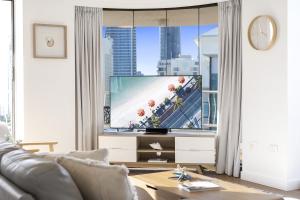 uma sala de estar com uma televisão e um sofá em Aegean Apartments - Q Stay em Gold Coast