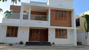 a white house with brown doors and windows at Tranquil Home in Trivandrum