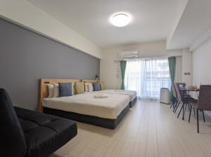大阪市にあるエスリードホテル難波サウスⅡのベッド2台とソファが備わるホテルルームです。