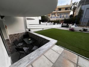 a patio with a table and chairs and a lawn at Bella Apartment in Pefkohori