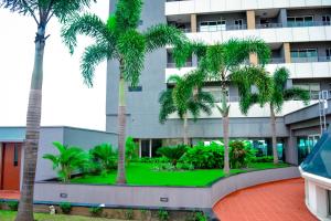 un edificio con palmeras delante en KingJada Hotels And Apartments Ltd en Dar es Salaam