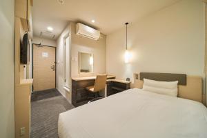 a hotel room with a bed and a desk at Via inn Kyoto Shijomuromachi in Kyoto
