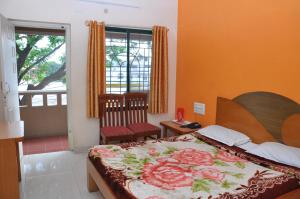 Un dormitorio con una cama con una manta de flores. en Vinayaka Deluxe Lodge en Kushālnagar