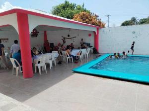 grupa ludzi siedzących wokół basenu w obiekcie alberca Blass w mieście Coatzacoalcos