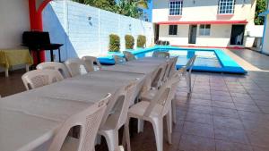a long table and chairs next to a swimming pool at alberca Blass in Coatzacoalcos