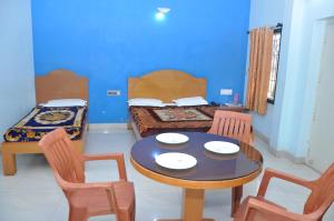 Pokój ze stołem, krzesłami i łóżkiem w obiekcie Vinayaka Deluxe Lodge w mieście Kushalanagar