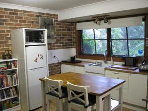 a kitchen with a table and a white refrigerator at Warriwul Farmland Rural Retreat BnB, Curramore/Jamberoo in Jamberoo