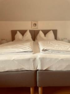 Una cama con sábanas blancas y almohadas. en Sonnenblumenhof, en Mühlheim