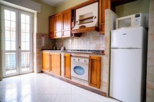 uma cozinha com armários de madeira e um frigorífico branco em Relaxing House em Lido di Ostia