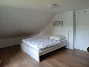 a bedroom with a white bed in a attic at Welcoming holiday home by the sea in Godern