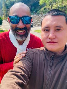 un hombre de pie junto a un hombre con gafas de sol en Pema Dekey monastic guest house, en Dirang Dzong