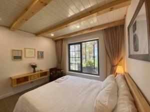 a bedroom with a large white bed and a window at Biệt Thự Đà Lạt View Đẹp - Gần Chợ Đêm in Xuan An