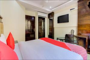 Hotel India continental في نيودلهي: غرفة نوم بسرير ابيض وتلفزيون