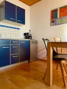 eine Küche mit blauen Schränken sowie einem Tisch und Stühlen in der Unterkunft Sonnenblumenhof in Mühlheim