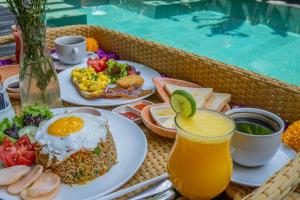 a table with plates of food and a glass of juice at djabu Seminyak Hotel in Seminyak