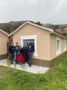 un grupo de personas parados frente a una casa en Quinuawasi House, en Ocosuyo