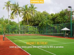 a tennis court with a net and palm trees at The Standard, Huruvalhi Maldives in Raa Atoll