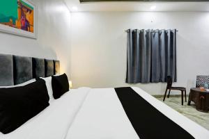 a bedroom with a black and white bed and a chair at OYO Flagship The Ashoka hotel restaurant and banquet in Kānpur
