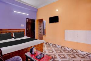 - une chambre avec un lit et une télévision murale dans l'établissement OYO Flagship HOTEL OM PALACE & BANQUET HALL, à Deoghar