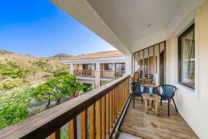 a balcony of a house with two chairs and a table at Southern Sun Homestay North in Kenting