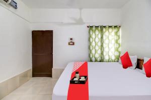 a bedroom with a bed with red and white at OYO Grand Royals Anjuna Near Anjuna Beach in Anjuna