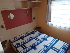 Cama en habitación pequeña con ventana en Camping le Bois Jahan en Brunelles
