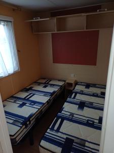 dwa puste łóżka w pokoju z oknem w obiekcie Camping le Bois Jahan w mieście Brunelles