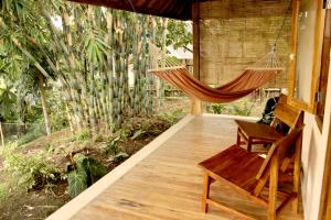a porch with a hammock and a chair on it at Santai House in Tetebatu