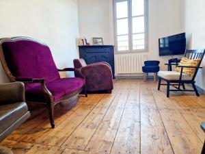 sala de estar con sillas, TV y suelo de madera. en Au Pont Vieux, en Espalion