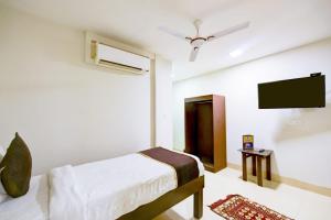 a bedroom with a bed and a flat screen tv at Chauhan Hospitality IGI Airport New Delhi Mahipalpur in New Delhi