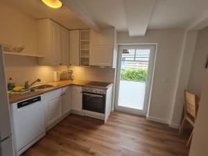 a kitchen with white cabinets and a sink and a window at Fewo "Marienleuchte" in Bannesdorf auf Fehmarn in Fehmarn