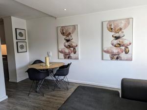 Habitación con mesa, sillas y pinturas en la pared. en Modern Retreat in District Six en Ciudad del Cabo