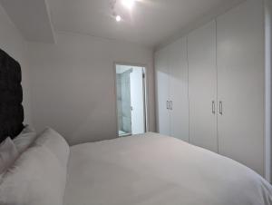 a white bedroom with a white bed and a window at Modern Retreat in District Six in Cape Town