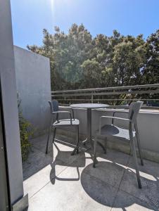 een tafel en 2 stoelen op een balkon met bomen bij Modern Retreat in District Six in Kaapstad